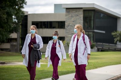 DVM students walking outside in white coats
