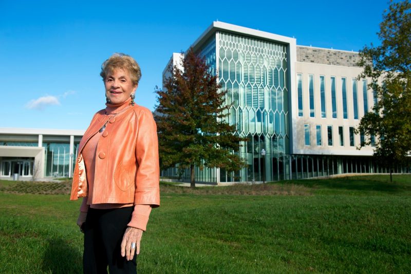 A woman stands in front of a large building on Virginia Tech's Blacksburg campus