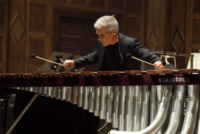 A man playing a marimba, holding two mallets in each hand.