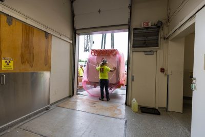 Two workers moving part of a new MRI machine down a hallway.