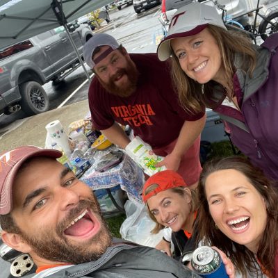 Group of people in Hokie gear, tailgating in a parking lot.