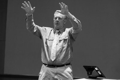 Black and white photo of a man speaking at a conference.