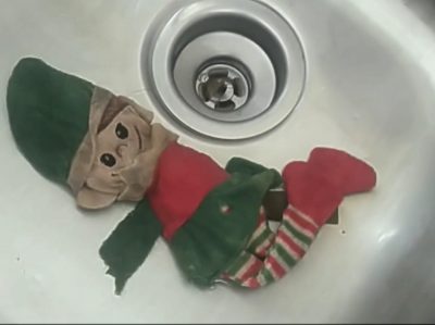 Stuffed elf in a sink.
