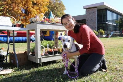 A veterinary student with a shite dog outside the college at an outdoor fundraising event.