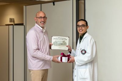 Dean Dan Givens presents the August 2023 Staff Member of the Month award to Raymond Lin.