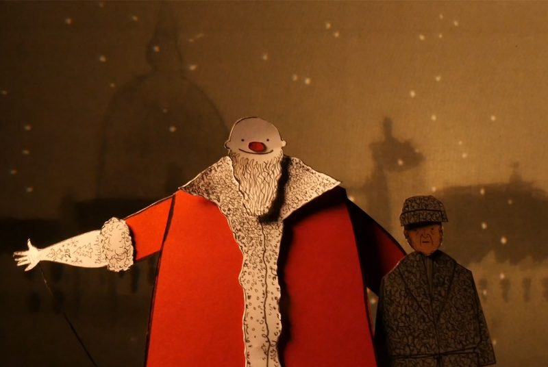 A puppet version of Santa with his arm outstretched stands beside a puppet version of Scrooge in this scene from Manual Cinema's "Christmas Carol."