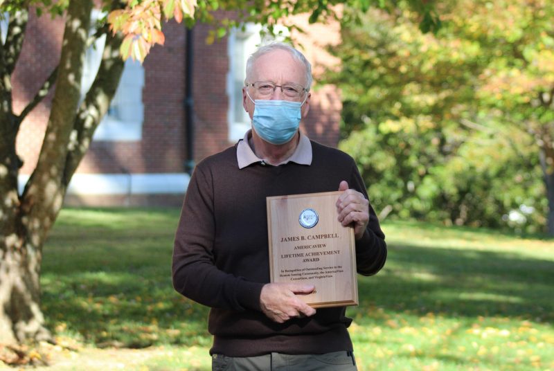 James Campbell wearing a face covering and holding a plaque