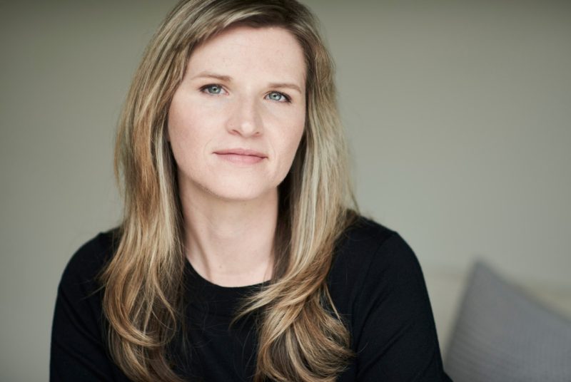 Author Tara Westover poses in a black sweater in front of an off-white background.