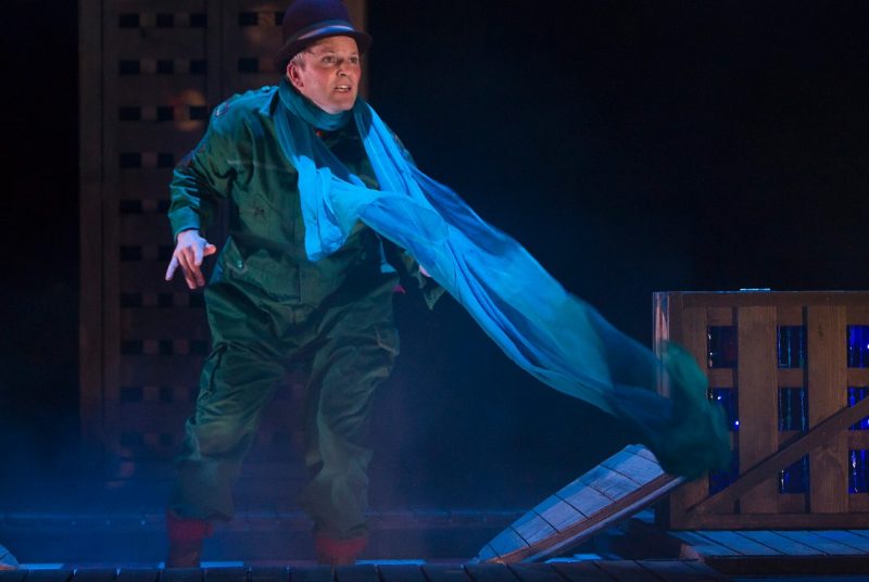 Performer Louis Lovett wears a hat and flowy scarf as he navigates boxes onstage for the production "The Girl Who Forgot to Sing Badly."