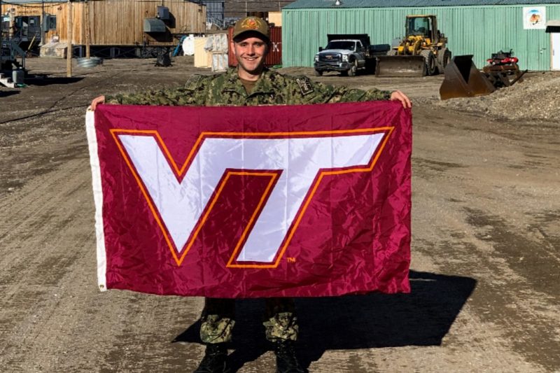 U.S. Navy Lt. j.g.  Kyle Luchau holds a Virginia Tech flag.