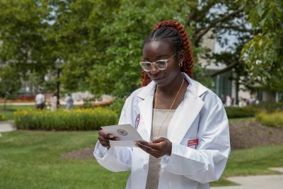 Student reads a welcome to the college note at the DVM Class of 2026 White Coat Ceremony.