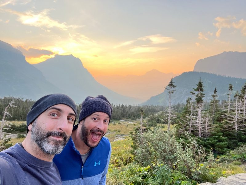 Two people at Glacier National Park with the sunrise in the background.