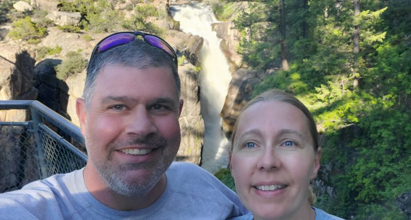 Two people with a waterfall behind them.