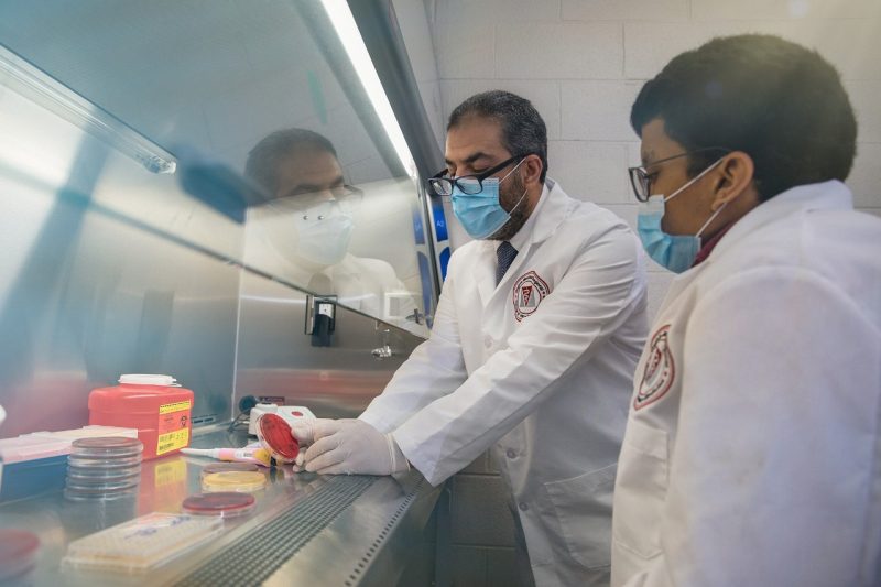 Two researchers in their white coats, working in a lab.