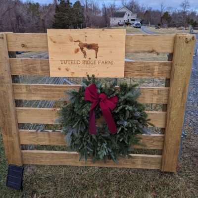 Wooden fence with a wreath and sign that says "Tutelo Ridge Farm".